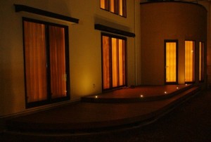 ウッドデッキの夜景写真。 上の段にはデッキライト（タカショー）を使用。 高さ、段差があるので、境目にライトを設置する事によって 安全面でも効果を発揮します。 柔らかな光が温かく包まれ、夜でも、ウッドデッキ上の時間が楽しめます。