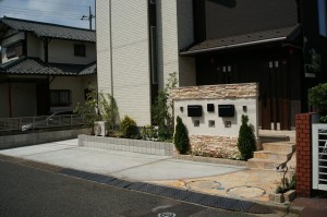 2世帯住宅で華やかな雰囲気の門周りというご希望により、重厚感がありながらもソフトな色合いの石張りを上下に施した門壁としました。